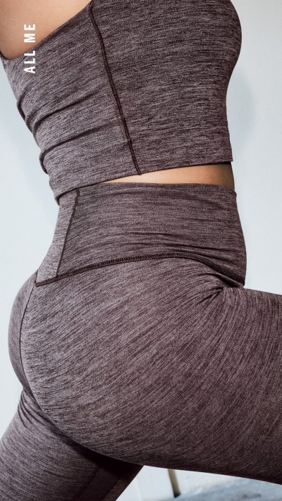 Das Bild zeigt eine Nahaufnahme des unteren Körpers einer Person, die eng anliegende, dunkle Sportbekleidung trägt. Die Kleidung scheint aus einem stretchigen, strukturierten Material zu sein und wird um den Mittelteil und die Beine der Person gewickelt, um die Konturen des Körpers hervorzuheben.