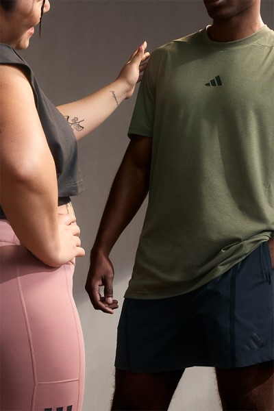The image shows two people, one wearing a green t-shirt and the other wearing a pink outfit, standing close together and interacting in an intimate manner.