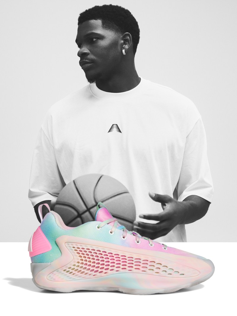 Anthony Edwards in a white shirt stands holding a basketball, with a pair of colorful, futuristic-looking sneakers in the foreground.