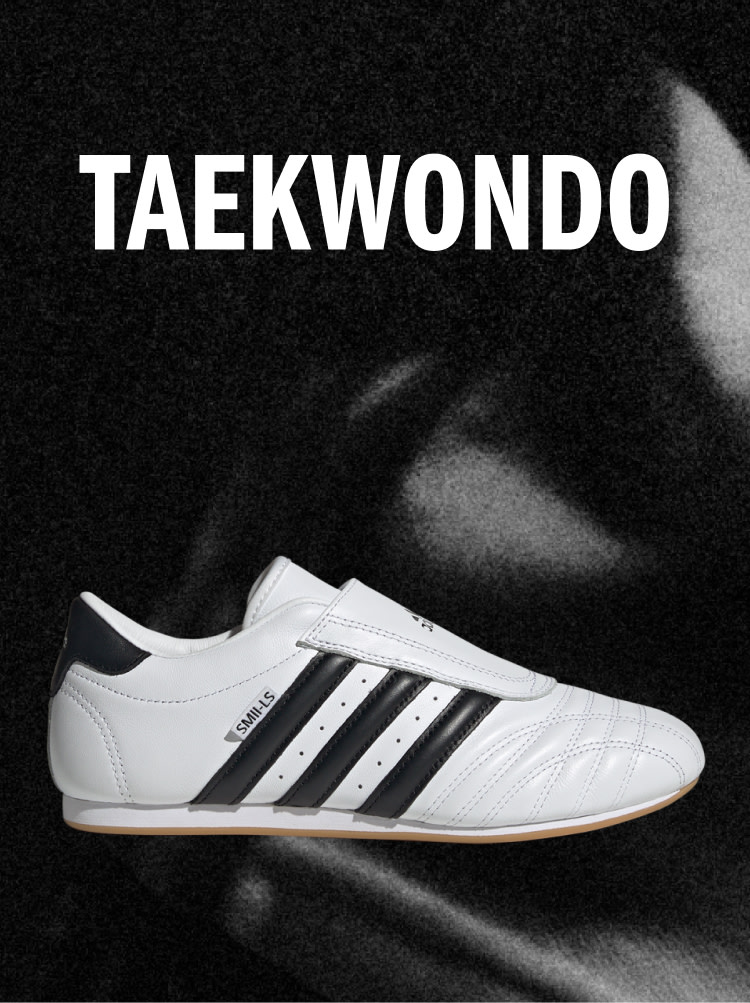 White Adidas Taekwondo sneaker with black stripes on a dark background, with the word TAEKWONDO above.