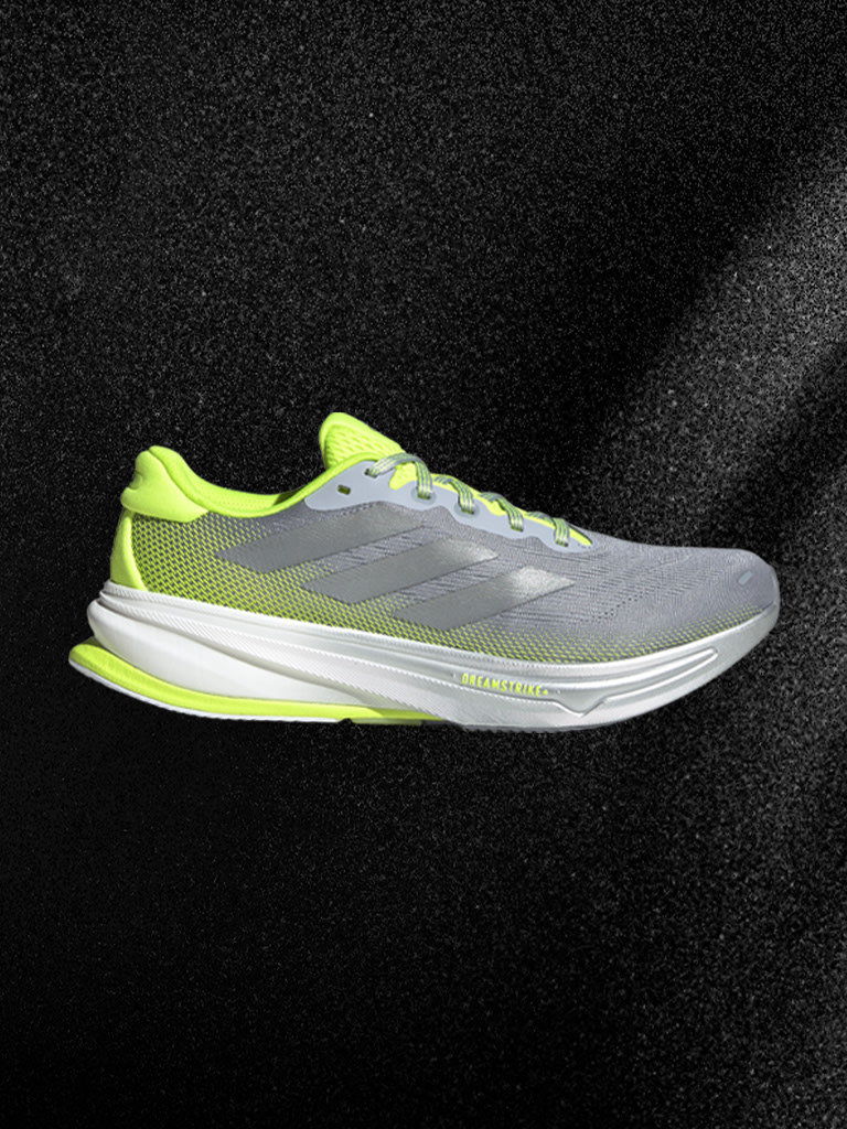 Une chaussure de sport gris et jaune fluo sur un fond sombre.