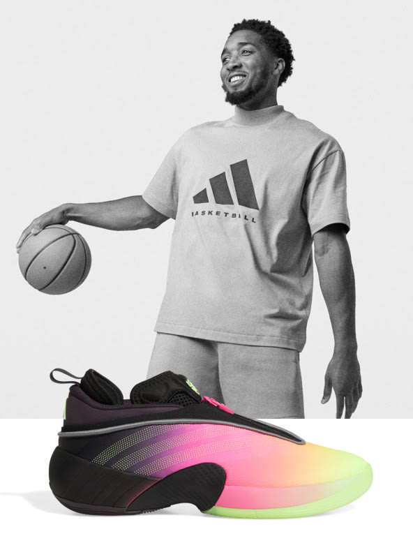 A smiling man in a gray t-shirt holding a basketball stands next to a pair of colorful, futuristic-looking sneakers on a plain background.