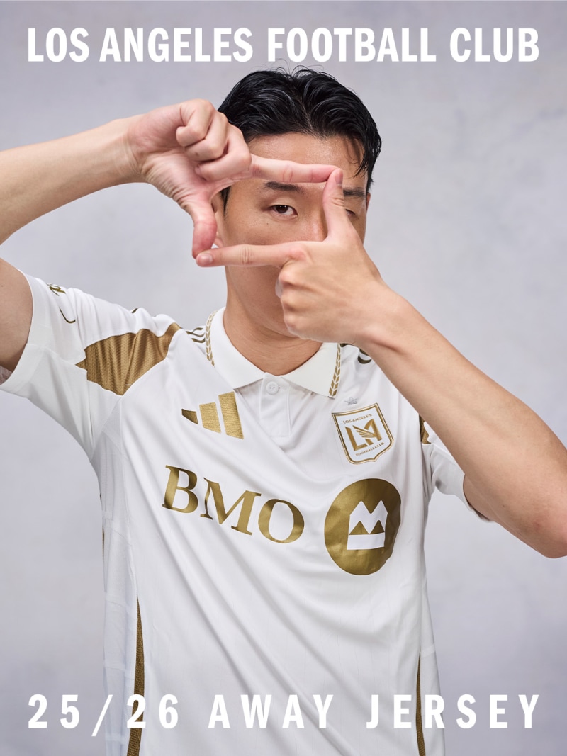 The image shows a person wearing a white soccer jersey with the Los Angeles Football Club logo and the text "BMO" prominently displayed. The person is making a framing gesture with their hands, creating a visual frame around their face.