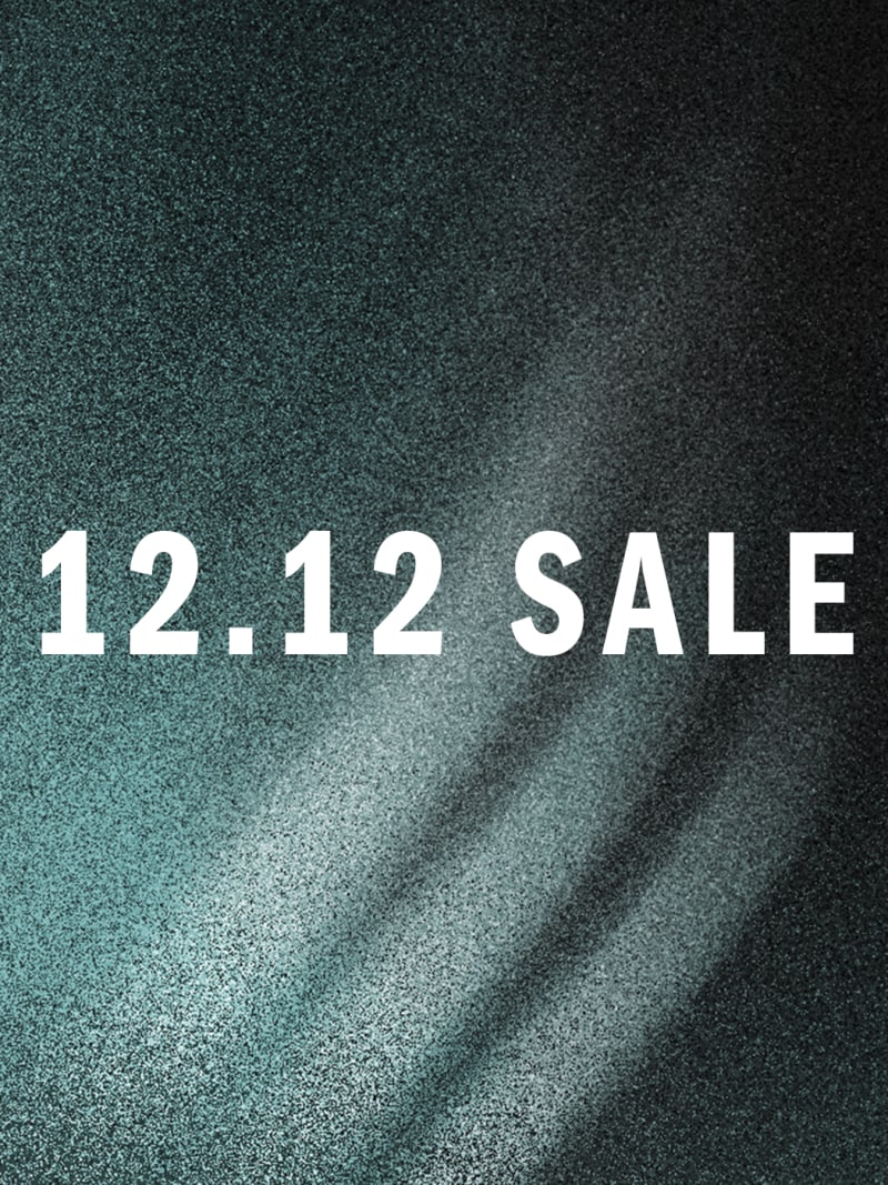 The image displays the text "12.12 SALE" prominently in the foreground against a blurred, textured green background.