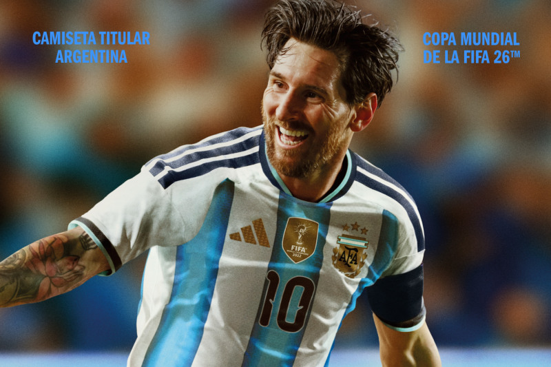 The image shows a smiling man wearing an Argentina national team jersey, with the FIFA World Cup 26th logo visible in the background.