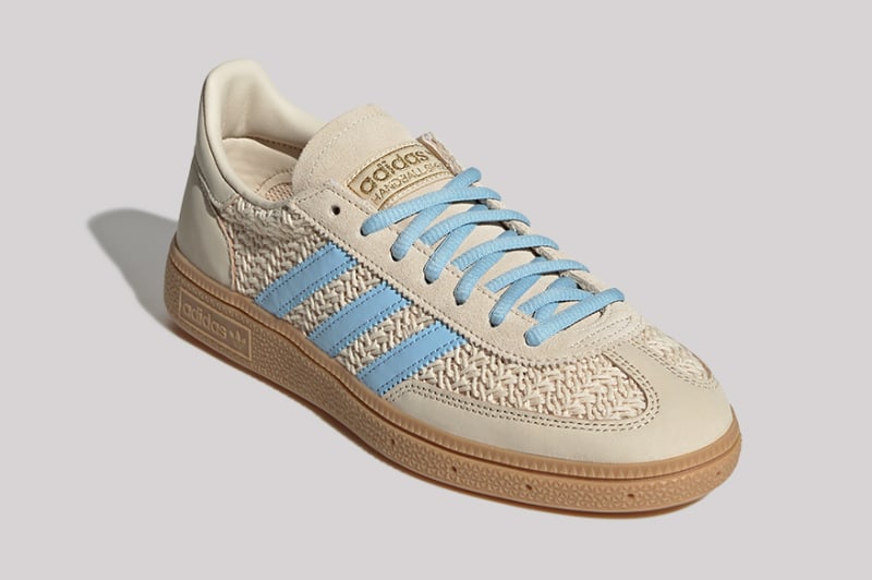 A pair of beige and blue Adidas sneakers with a textured pattern on the upper, resting on a plain background.