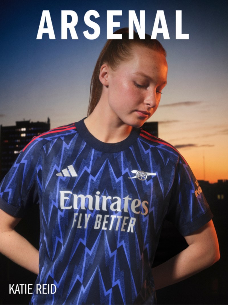 The image shows a young woman wearing an Arsenal soccer jersey, standing in front of a sunset backdrop.