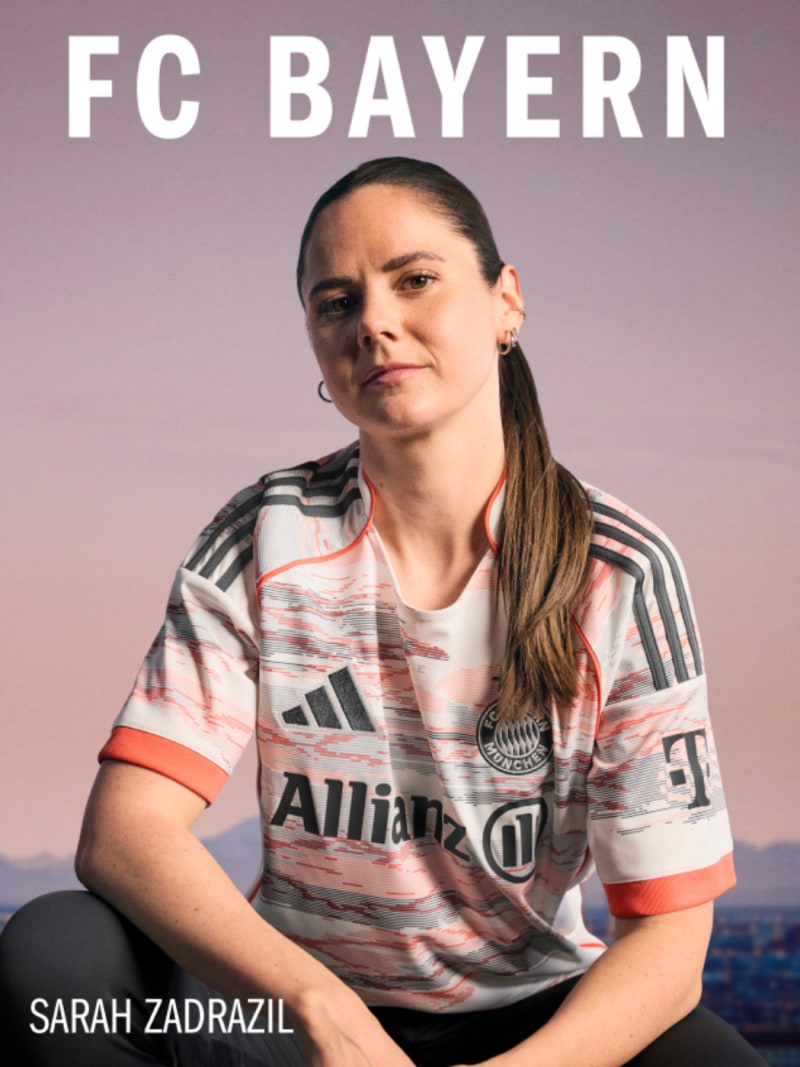 The image shows a woman wearing a Bayern Munich soccer jersey, sitting outdoors against a backdrop of a sunset sky.