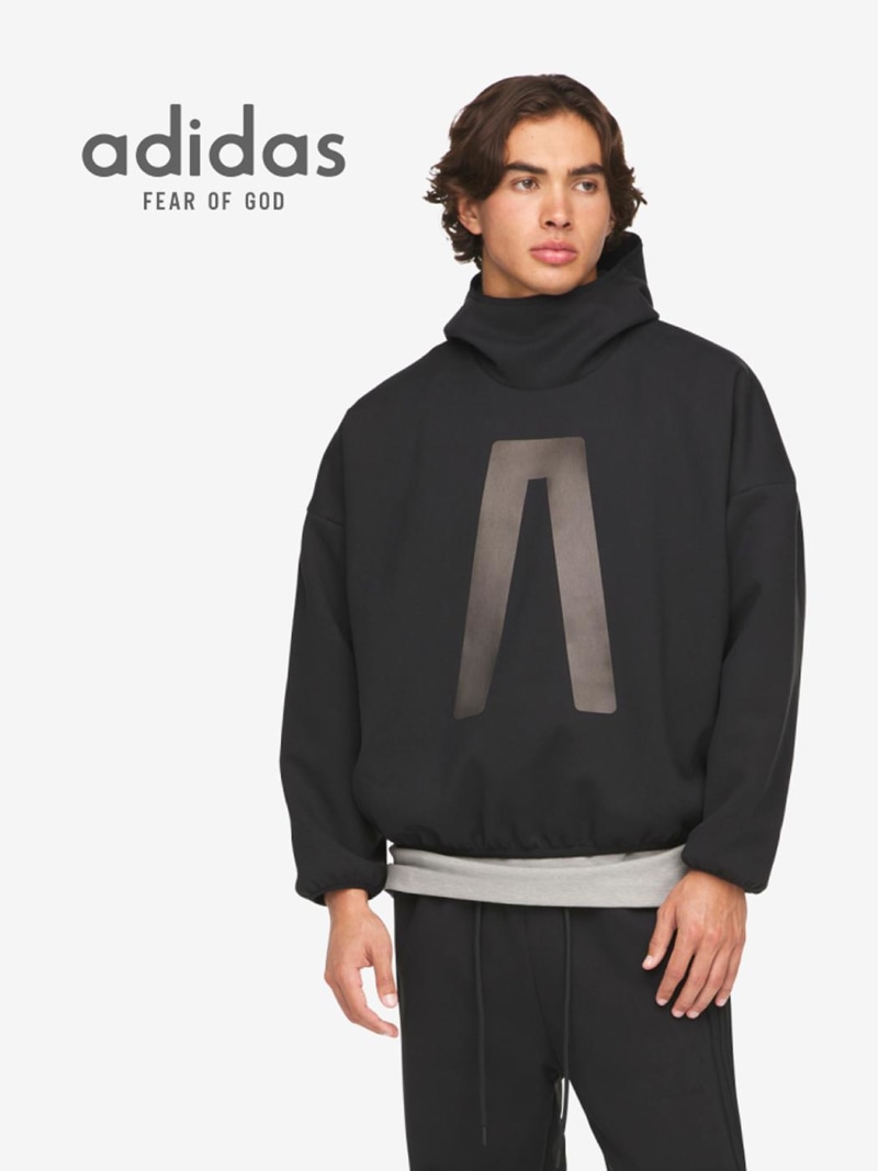 The image shows a person wearing a black Adidas sweatshirt with the "Fear of God" logo prominently displayed.