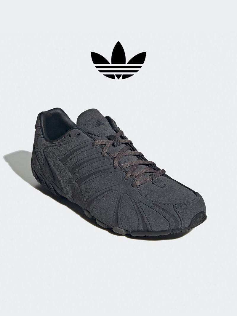 The image shows a pair of dark gray Adidas sneakers with the iconic Adidas trefoil logo prominently displayed in the background.