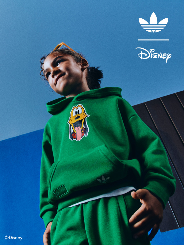Close up of child outside with a blue backdrop, wearing the adidas | Mickey & Friends collection