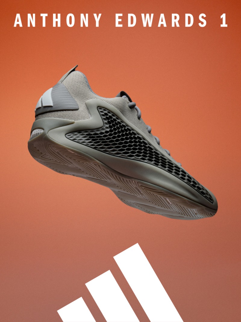 The image shows a gray and black athletic shoe with a textured sole, set against an orange background.