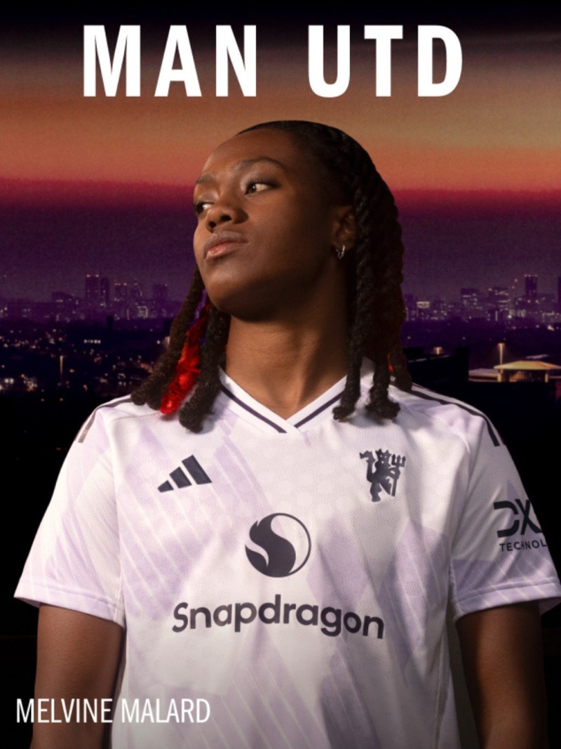 The image shows a person wearing a white Manchester United soccer jersey with the Snapdragon logo, standing in front of a cityscape with a vibrant sunset sky.