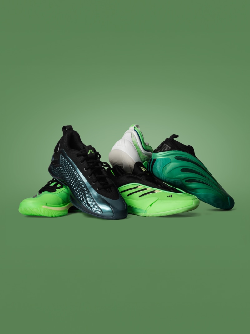 A pair of vibrant green and black athletic shoes with intricate designs and patterns, set against a solid green background.