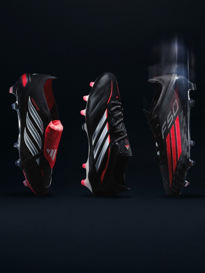 Three pairs of sleek, high-performance soccer cleats in black, red, and white colors stand out against the dark background, showcasing their bold and dynamic design.