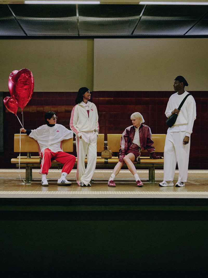 The image shows a group of people sitting on a bench, with one person holding a red balloon. The background appears to be a stage or performance area, with a dark curtain or backdrop visible.