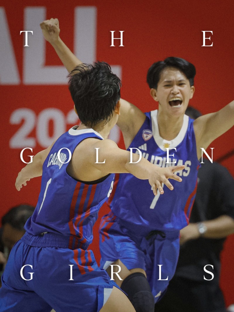 Two basketball players in blue jerseys celebrating on a basketball court with a red background displaying the text "The Golden Girls".