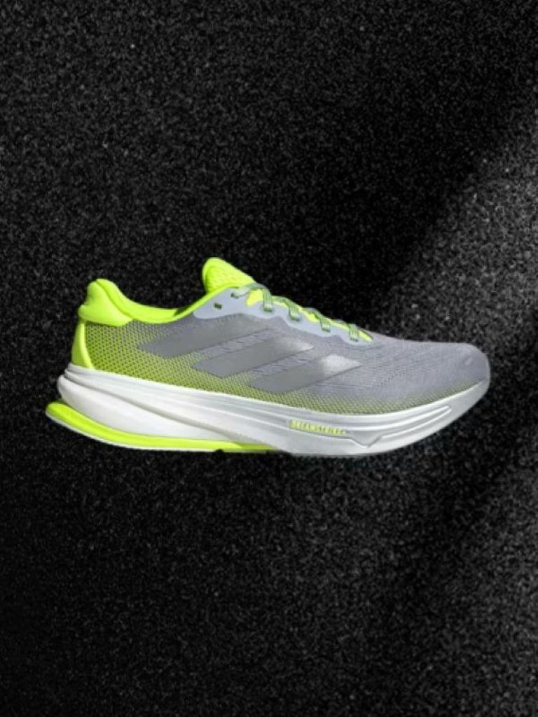 A gray and neon yellow athletic shoe against a dark background.