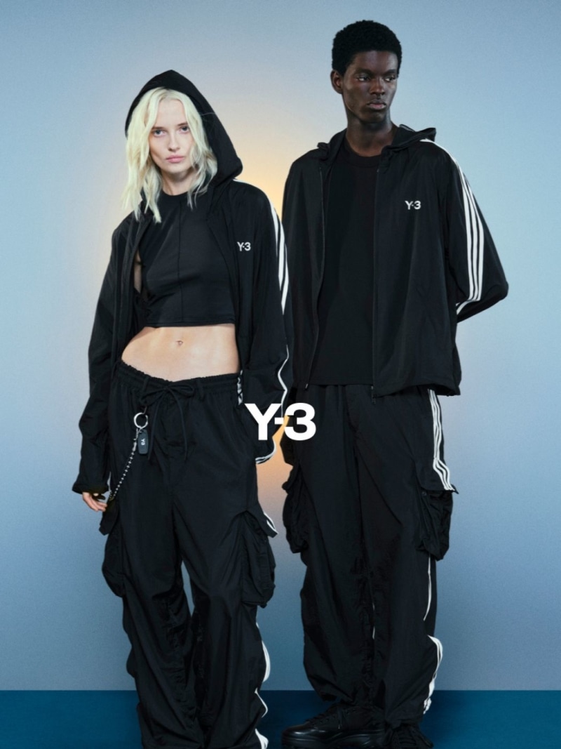 Two individuals wearing black Y-3 athletic apparel stand against a blue and gray background.