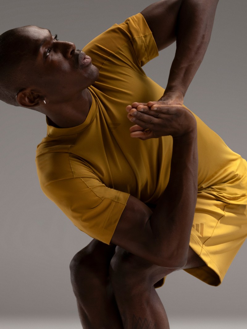 Man wearing adidas training gear performs dynamic exercise.