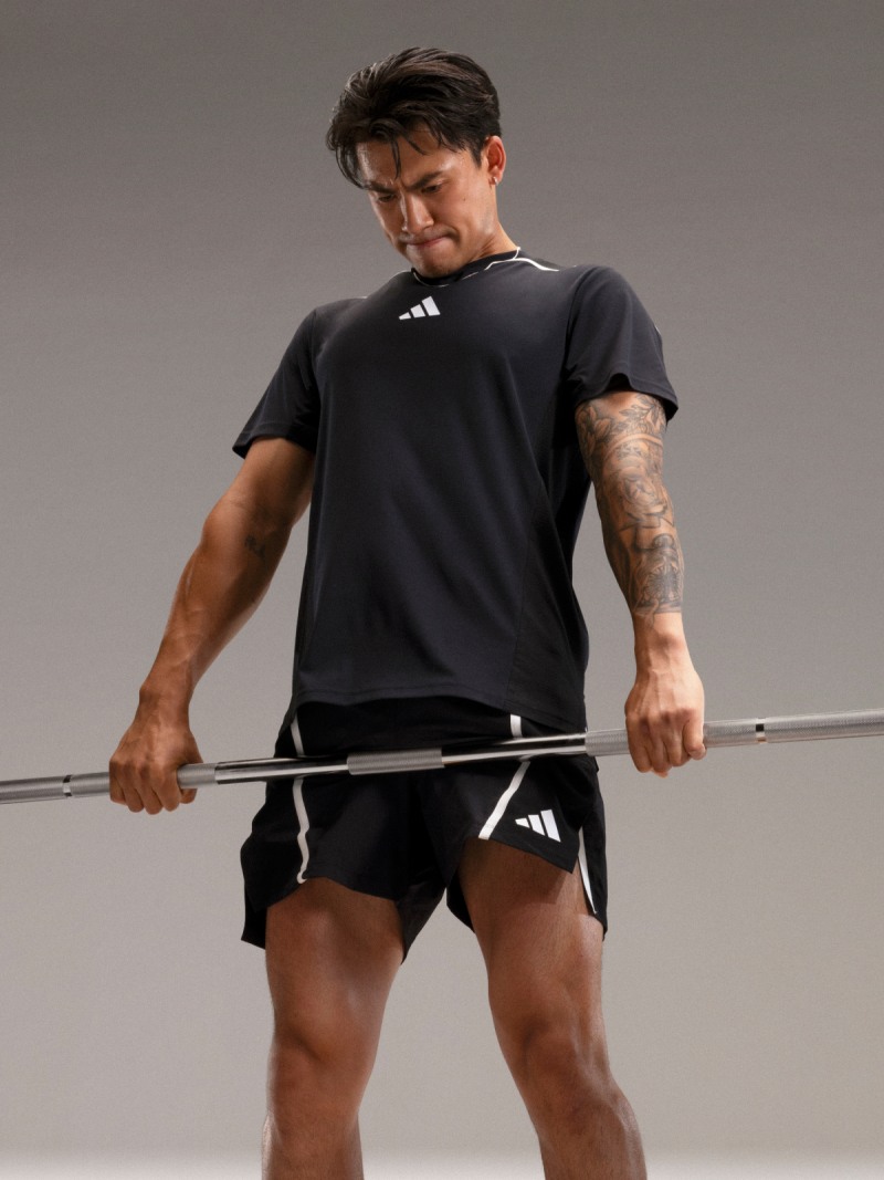 Man wearing adidas training gear performs deadlift.