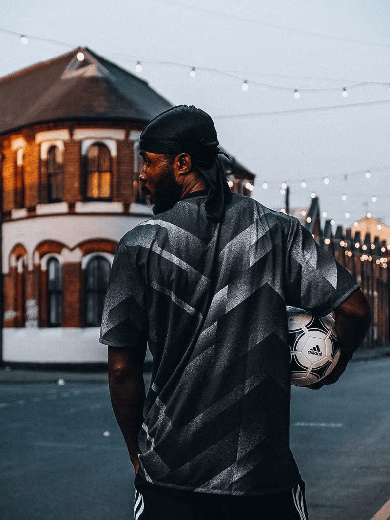 A man with a football ball under his arm in front of a building 