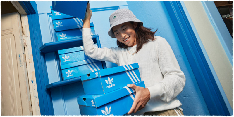An image with a man holding two boxes in his hands against the background with more boxes