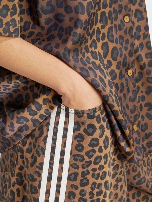 A leopard-print garment with white stripes covers a person's arm, revealing a portion of their leg.