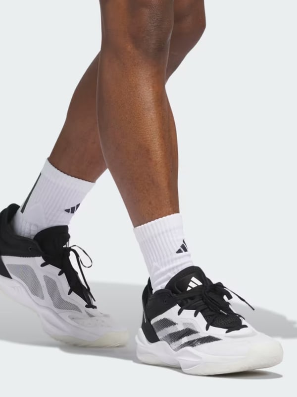 The image shows a person's lower body wearing white socks and black and white athletic shoes, standing on a plain white background.