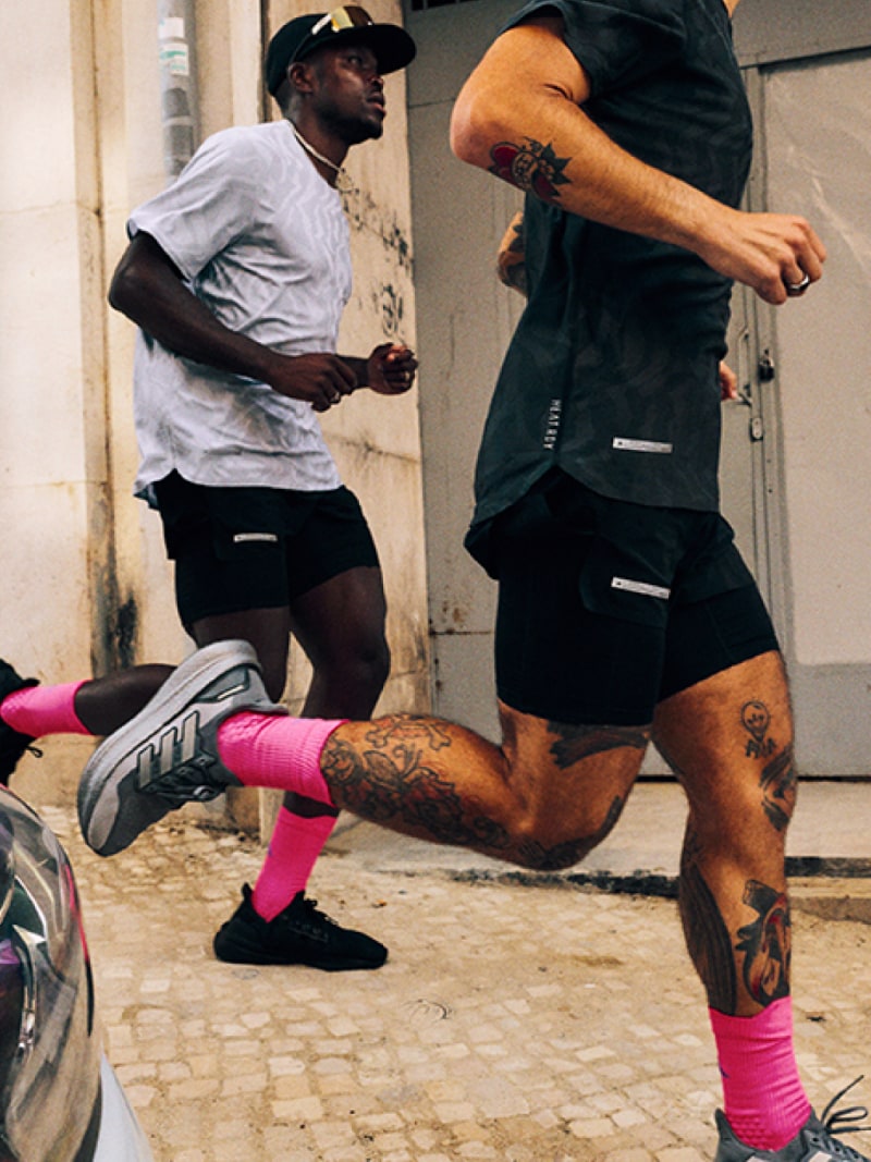 Two individuals, one wearing a white shirt and the other wearing black shorts, are engaged in what appears to be a physical activity or exercise in an indoor setting with a tiled floor.