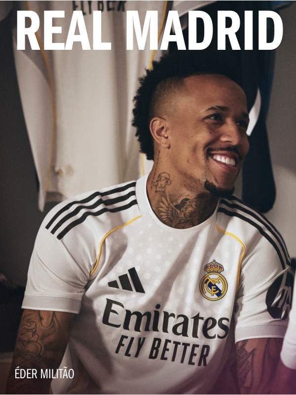The image shows a smiling man wearing a white Real Madrid soccer jersey with the "Emirates" logo, standing in front of a white background.
