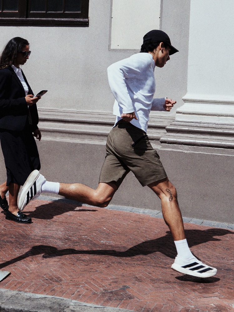 Two individuals, one wearing a white shirt and the other a black jacket, are engaged in an interaction on a brick-paved surface in an urban setting.