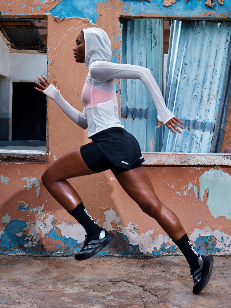 A person in athletic clothing is running in front of a dilapidated building with peeling paint and a damaged wall.