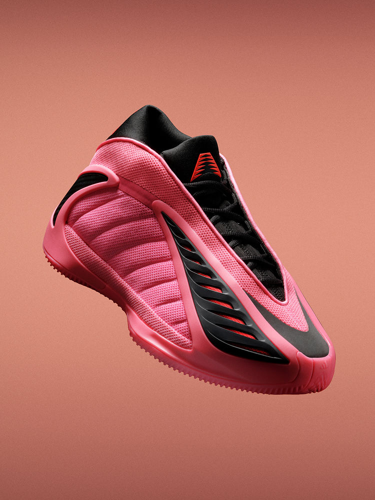 Zapatilla de baloncesto adidas Anthony Edwards 2 rosa y negro sobre un fondo naranja. Presenta una suela esculpida y un diseño ondulado. 