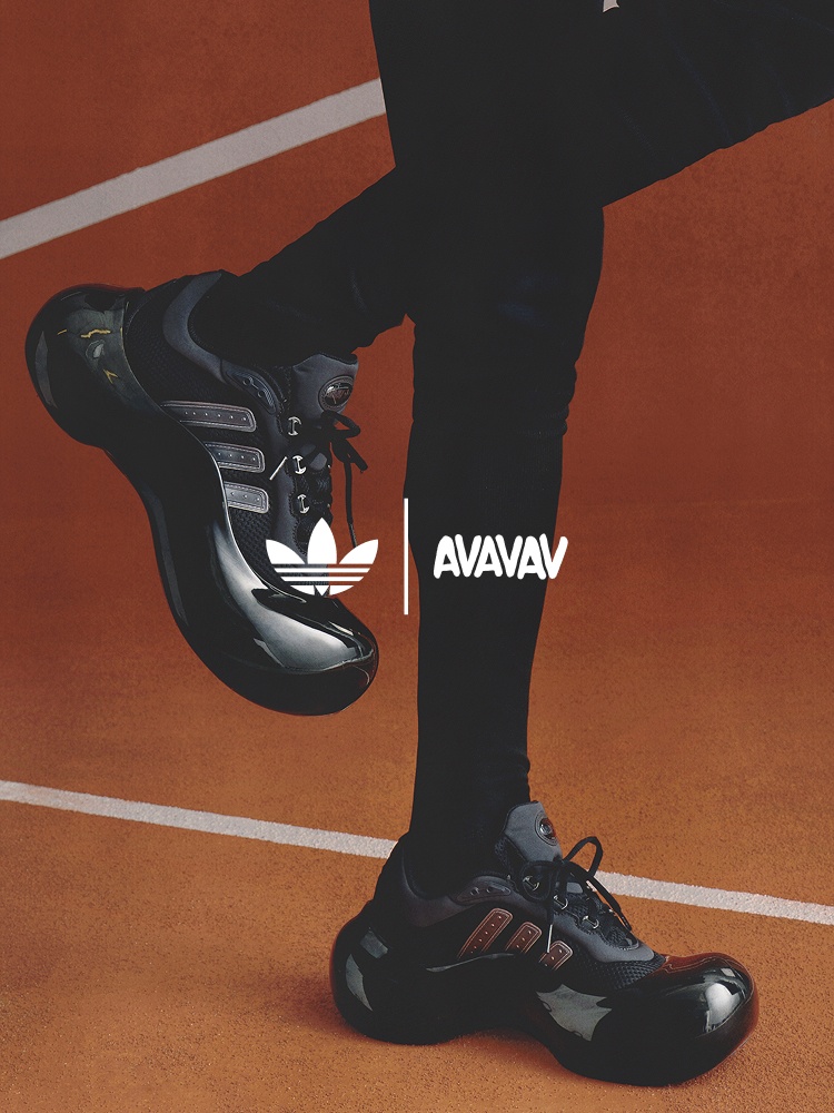 The image shows a pair of black and white Adidas sneakers on a person's feet, set against an orange and black background with the Adidas logo prominently displayed.