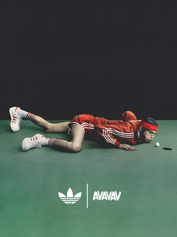 A person in a red and white athletic uniform is lying on a green surface, with the Adidas Avavav logo visible in the background.