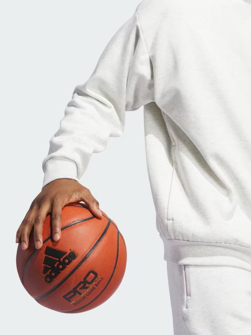 A person's hand holding a basketball against a plain white background.