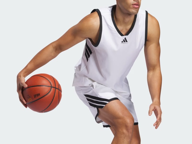 A basketball player in a white jersey is holding a basketball and appears to be in motion on a plain background.