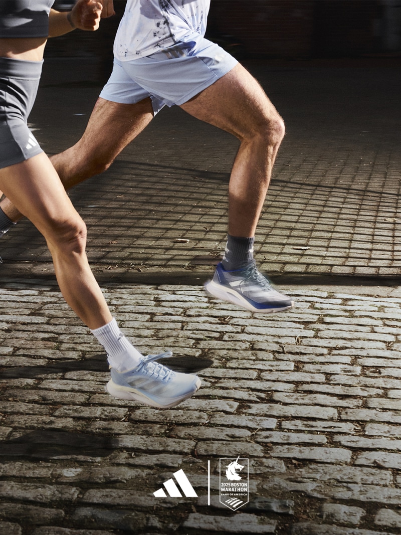 The image shows a person's lower body wearing athletic shoes and clothing, standing on a wooden surface with the Adidas and Parley logos visible.