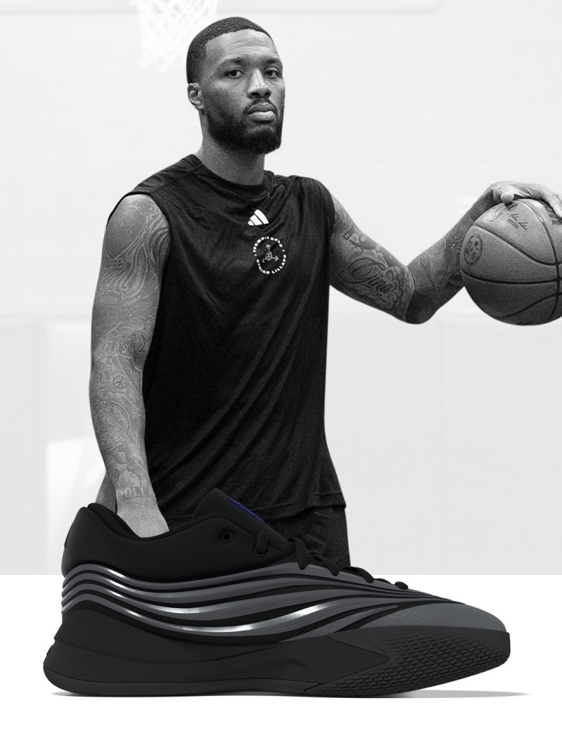 Un hombre negro con una camisa deportiva y pantalones cortos negros, sentado en una esterilla de ejercicio negra y sosteniendo un balón de baloncesto.