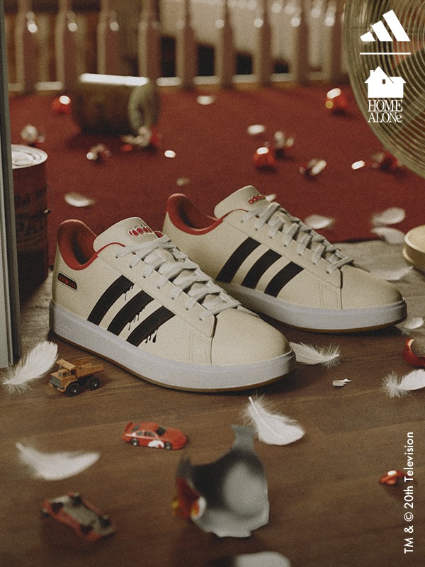 รองเท้าสีครีม สีดำ และสีแดงสำหรับชุดเหย้าของอาดิดาสที่อยู่ตรงกลางของฉากวันหยุดแสนยุ่งเหยิง กับเครื่องประดับคริสต์มาสแตกสลาย รถของเล่น และกระป๋องสีที่พลิกคว่ำ