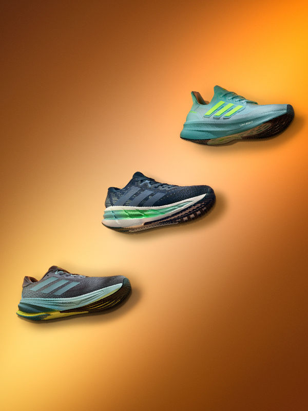 Three pairs of running shoes in various shades of blue and green against an orange background.