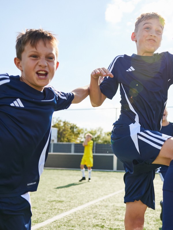 Two boys jumping in the air during football practice