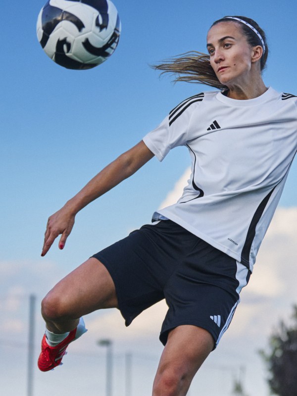 Female player kicking an adidas ball while wearing Predator boots