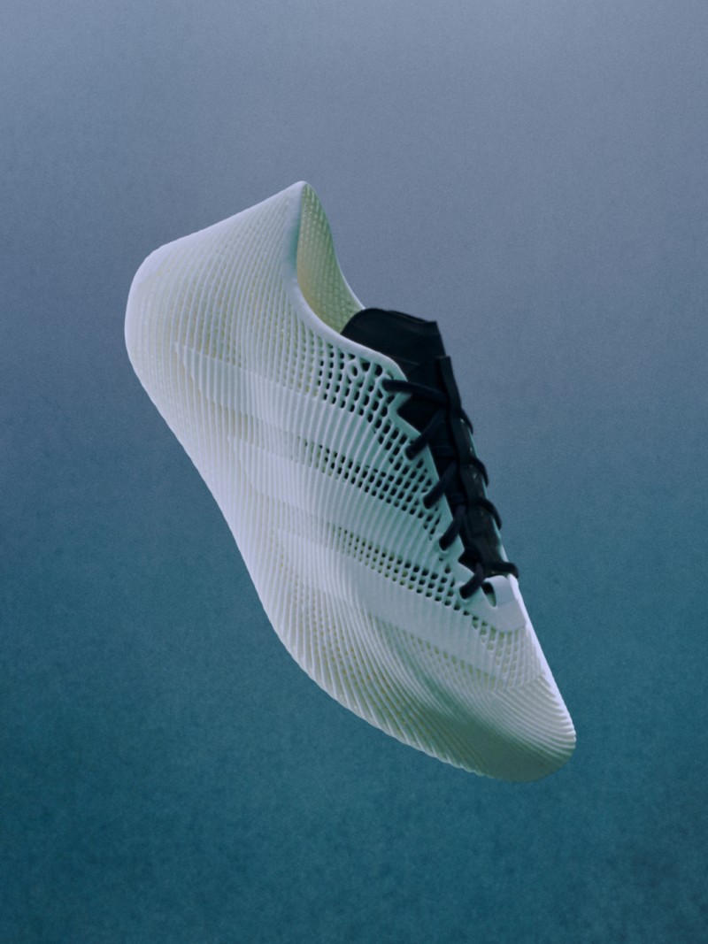 Una scarpa sportiva bianca e verde con un esclusivo motivo in mesh risalta su uno sfondo blu scuro.