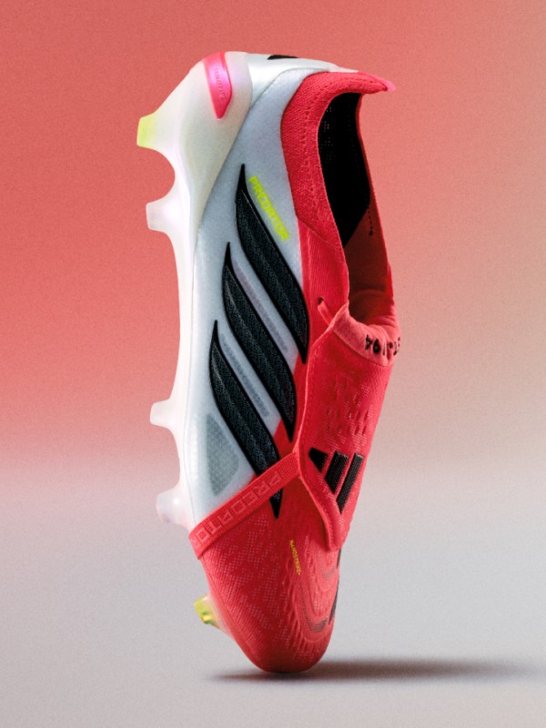 A vibrant, red and white athletic shoe with black and yellow accents, set against a plain coral-colored background.