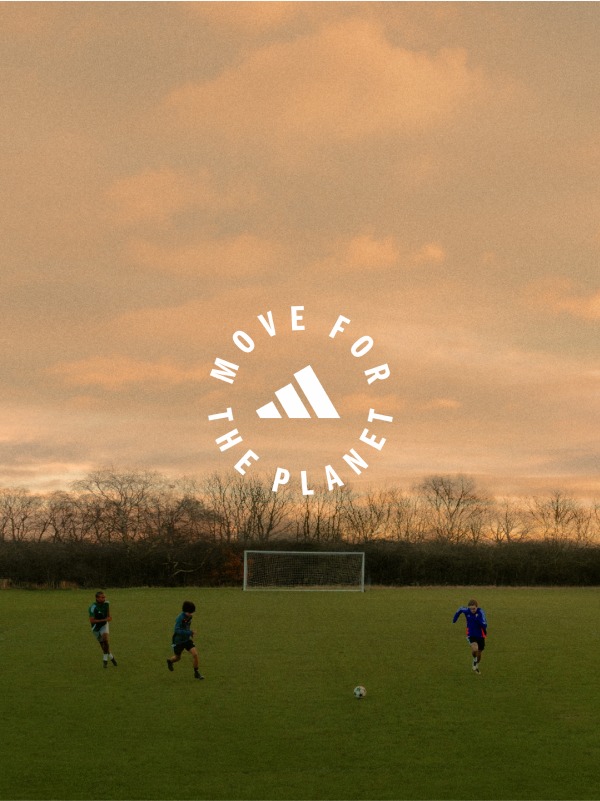The image shows a soccer field with a goal post in the foreground, and in the background, there is a cloudy sky with an orange-tinted sunset.