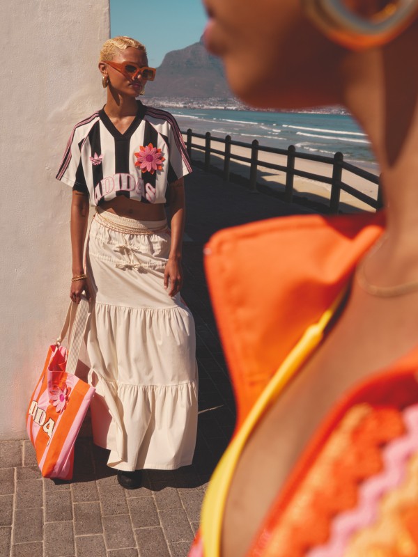 A photo of two models standing on a promenade next to the ocean wearing the adidas 2025 Summer Glow collection.