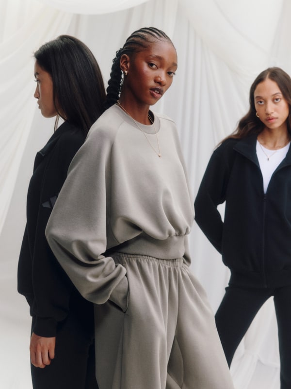 Three young women, dressed in stylish monochrome outfits, stand against a plain white backdrop, exuding a sense of modern elegance and minimalism.