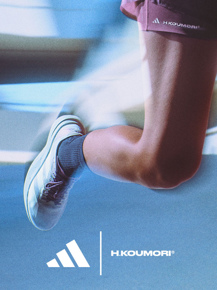 The image shows a person's lower body wearing Adidas athletic clothing and shoes, with the Adidas Houmori logo visible, against a blurred blue background.